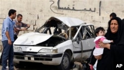 Warga mengamati sebuah mobil yang hancur di wilayah Zayona, sebelah Timur Baghdad (20/3). Dua orang tewas dan empat orang lainnya dilaporkan terluka dalam insiden yang bertepatan dengan peringatan 10 tahun invasi AS di Irak ini.