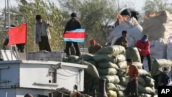 朝鲜人在新义州把货物装上一艘挂有朝中两国旗帜的船上。(资料照)