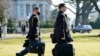 FILE - A White House military aide carrries the so-called nuclear football as he walks to board the Marine One helicopter with U.S. President Joe Biden at the White House in Washington, Feb. 16, 2021.