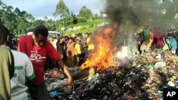 Bystanders watch as a woman accused of witchcraft is burned alive in the Western Highlands provincial capital of Mount Hagen in Papua New Guinea, February 6, 2013.