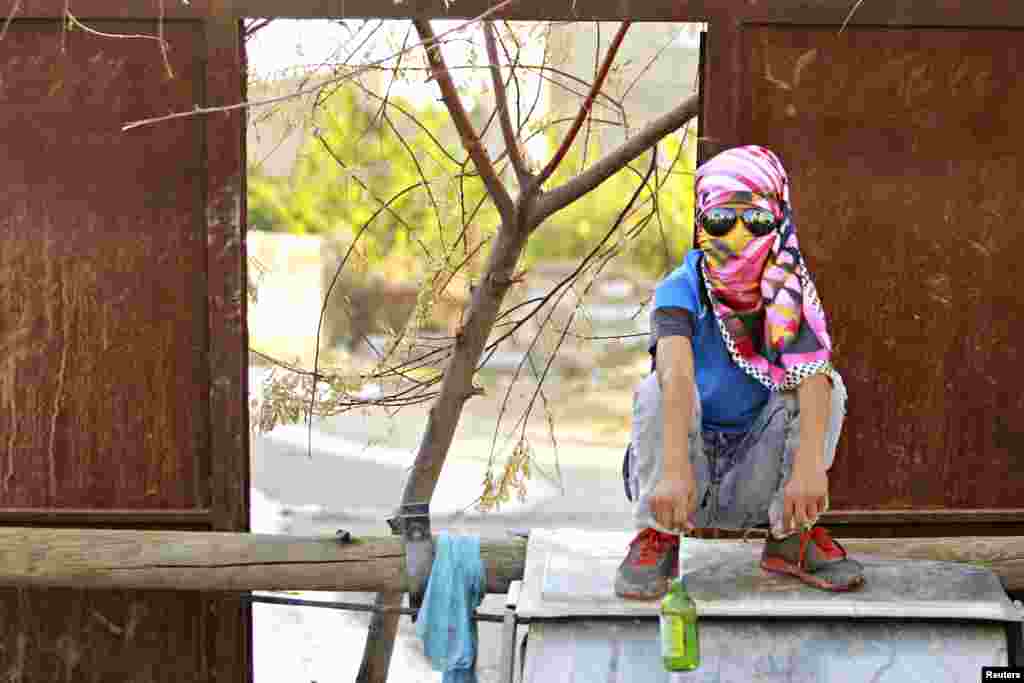 A masked Kurdish boy sits in front of a barricade that blocks a road in Van, eastern Turkey, Aug.27, 2015.