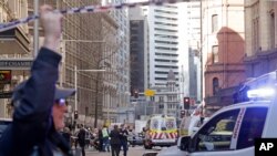 Emergency workers stand at a scene after a man, wielding a long knife, attempted to stab several people in Sydney, Australia, Aug. 13, 2019.
