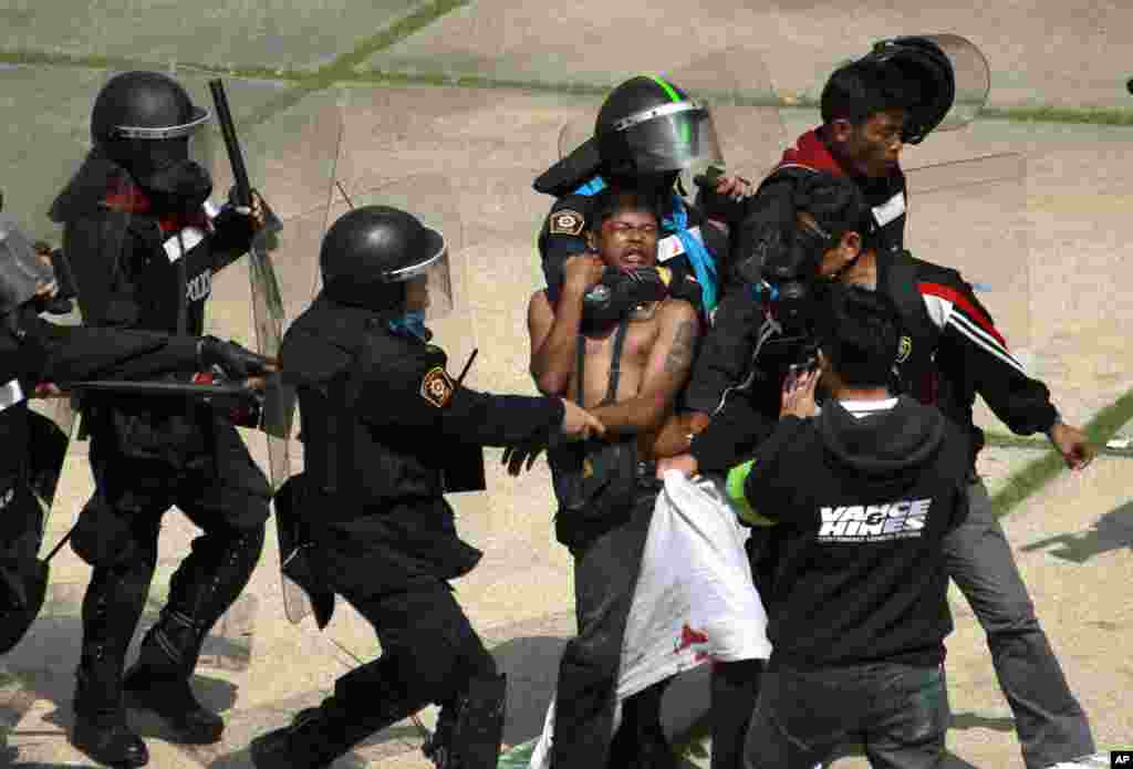 An anti-government protester is detained by riot police during a clash at a sports stadium in Bangkok, Thailand. Rock-throwing demonstrators trying to halt preparations for elections fought police in the capital, escalating their campaign to topple the country&#39;s beleaguered government.