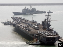 FILE - U.S. aircraft carrier USS Ronald Reagan anchors as U.S. Aegis Ship passes after they arrive at Busan port for joint military exercises in Busan, South Korea.