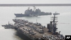FILE - U.S. aircraft carrier USS Ronald Reagan anchors as U.S. Aegis Ship passes after they arrive at Busan port for joint military exercises in Busan, South Korea.