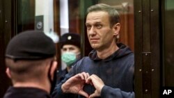FILE - Russian opposition leader Alexey Navalny makes a heart symbol standing in a court cage in Moscow on Feb. 3, 2021. (Moscow City Court via AP)