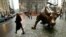 People pass the statue of the bull near Wall Street in New York, undated file photo.