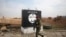 FILE - An Iraqi soldier walks next to a wall painted with the black flag commonly used by Islamic State militants, north of Mosul, Iraq, Jan. 21, 2017.