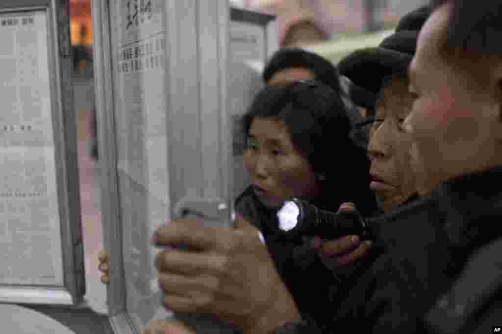 Seorang laki-laki Korea Utara menggunakan senter ketika ia dan penumpang kereta lainnya berkumpul di papan berita koran di sebuah peron kereta api di Pyongyang untuk membaca berita tentang Jang Song Thaek, paman dari pemimpin Korea Utara Kim Jong Un, yang dihukum mati dengan tuduhan pengkhianat. 