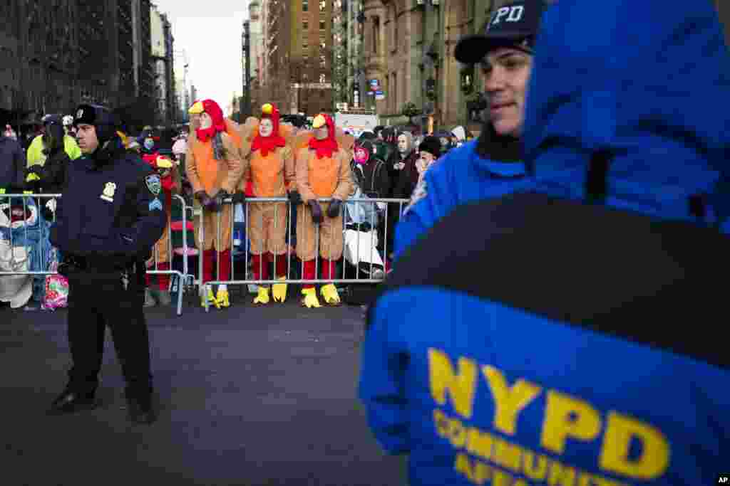 Para penonton memakai kostum kalkum berdiri di belakang barikade polisi saat menunggu Parade Hari Bersyukur Tahunan Macy&#39;s ke-87 di New York (28/11). (AP/John Minchillo)