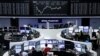 Traders work at their desks in front of the German share price index, DAX board, at the stock exchange in Frankfurt, Germany, April 12, 2016. 