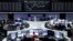 Traders work at their desks in front of the German share price index, DAX board, at the stock exchange in Frankfurt, Germany, April 12, 2016. 