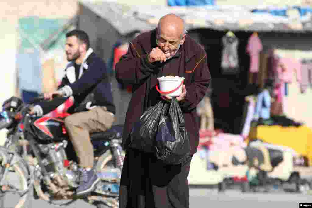 Seorang pria lansia makan makanan dari bantuan kemanusiaan di Aleppo, Suriah.