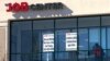 FILE - A man walks past the signs of an employment agency, March 2, 2021, in Manchester, N.H. 
