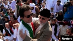 Ulama Sufi dan pempimpin partai politik Pakistan Awami Tehreek (PAT), Tahir ul-Qadri (kanan) menyambut Imran Khan, politisi oposisi Pakistan seusai sholat Idul Adha di depan gedung parlemen (Foto: dok).
