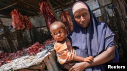 A Somali woman selling meat from a kiosk holds her child in a market area in the centre of the southern port city of Kismayo, south of Mogadishu, October 7, 2012 