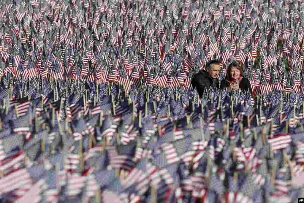 Sepasang warga Amerika memotret diri mereka sendiri di antara lautan bendera di sebuah pelataran di Boston, 26 Mei 2013. Bendera tersebut dipajang untuk mengenang warga Massachusetts yang gugur dalam perang, sejak Perang Saudara hingga saat ini, dengan dukungan dana dari &quot;Massachusetts Military Heroes Fund&quot;. (AP Photo / Michael Dwyer)