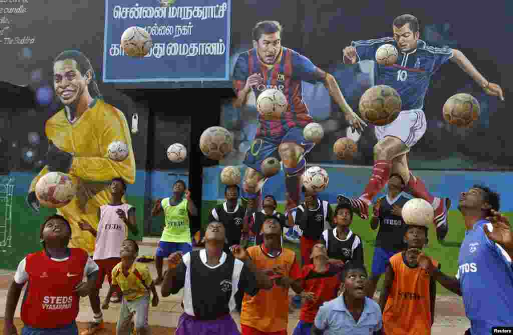 Anak-anak India berlatih menyundul bola, di depan lukisan mural Ronaldinho, Lionel Messi dan Zinedine Zidane di kota Chennai.