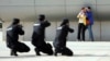 Police officers take aim with their weapons at a man playing the role of an attacker as he holds a woman hostage during an anti-terrorism drill at a railway station in Zhengzhou, China, May 7, 2014.