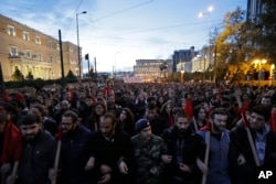 Backdropped by the Greek Parliament, left, demonstrators march in central Athens,Nov. 17, 2017.