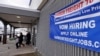 FILE - A 'Now Hiring' sign hangs on the front wall of a Harbor Freight Tools store in Manchester, New Hampshire, Dec. 10, 2020.