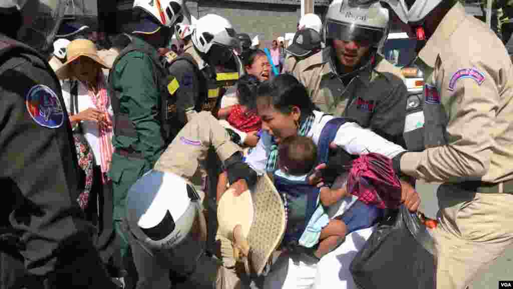 ក្រុម​សន្តិសុខ​កំពុង​ទាញ​ និង​អូស​ប្រជា​​ពលរដ្ឋ​​​មាន​ទំនាស់​ដី​ធ្លី​ជាមួយ​​ក្រុមហ៊ុន​ចិន ​Union Dev​el​o​pm​ent Group (UDG) ដែល​តវ៉ាសុំ​អន្តរាគមន៍​​នៅ​មុខ​ស្ថាន​ទូត​ចិន​ ​ ​​ចេញ​ពីស្ថានទូត​ នា​ថ្ងៃទី​១៣ ខែសីហា​ ឆ្នាំ​២០១៩។ (កាន់ វិច្ឆិកា/VOA) 