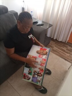 Torkwase Kuraun, Sister of missing journalist Tordue Salem, looks at pictures of him in the family photo album at her home in Abuja, Nov. 4, 2021. (T. Obiezu/VOA)
