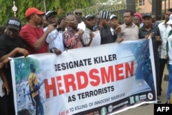 FILE - Demonstrators march and carry banner to protest bloody clashes between herdsmen and farmers in the vast central region that has claimed dozens of lives during a rally in Abuja, Nigeria, March 14, 2018.