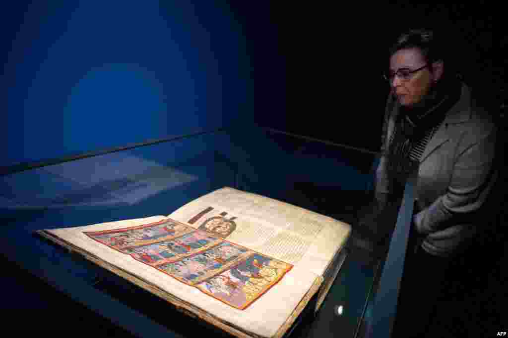 A journalist looks at the Moutier-Grandval Bible, a 9th century illustrated bible, one of the oldest fully preserved bibles in the world, during the press day of the exhibition "Sur les traces d’un chef-d’oeuvre: La Bible de Moutier-Granval" or ''On the t