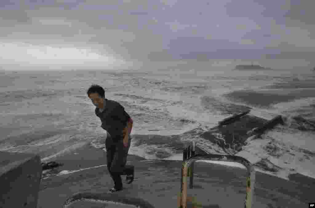 Seorang pria berjalan kembali dari pantai Enoshima, sementara topan kuat mendekati kota Fujisawa, dekat Tokyo.