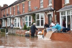People bail water out of flooded homes after the River Wye burst its banks in Ross-on-Wye, western England, Feb. 17, 2020, in the aftermath of Storm Dennis.