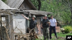 Anggota komite investigasi Rusia memeriksa sebuah rumah setelah mortir ditembakkan di kota Rusia, Donetsk, Minggu, 13 Juli 2014. 