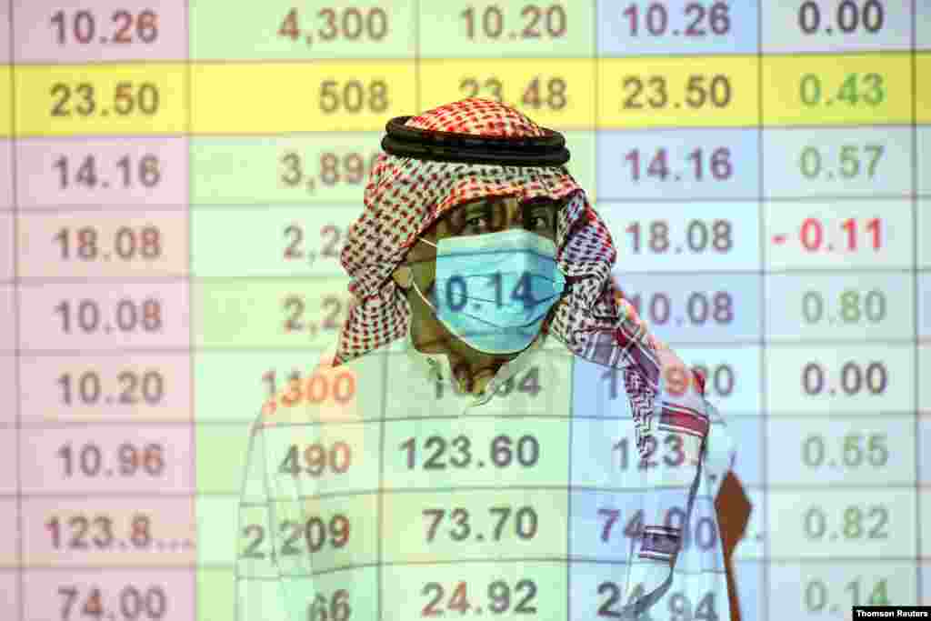 사우디아라비아 리야드에서 주식 투자자가 코로나바이러스 예방 마스크를 착용한 채 증권 거래 현황을 보고 있다. 