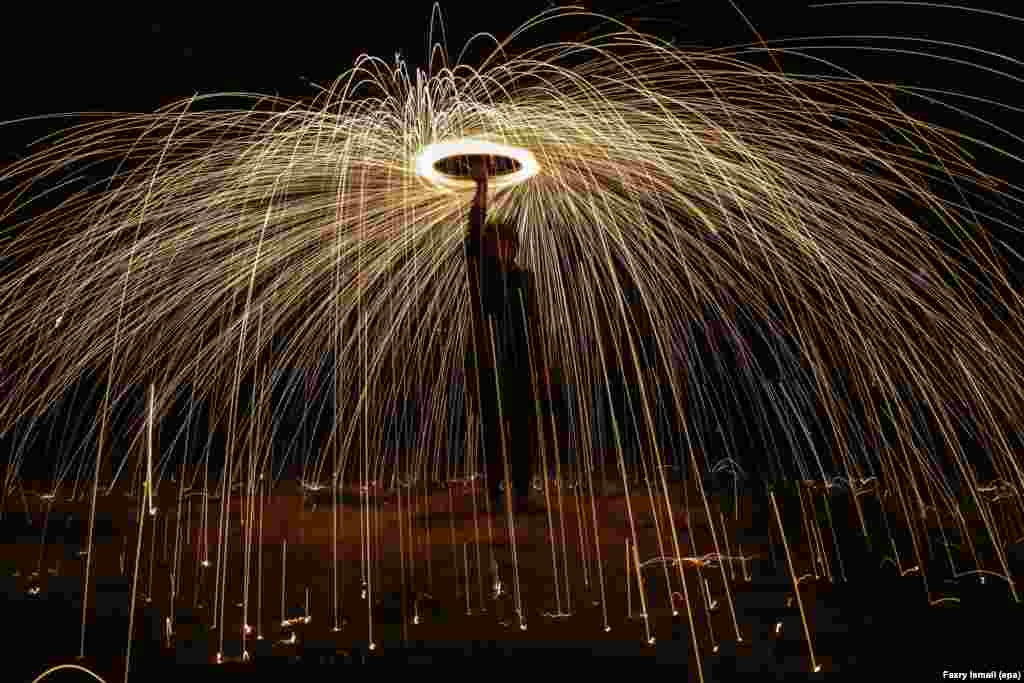 Seorang pria Malaysia membakar kembang api untuk menyambut Idul Fitri di Shah Alam, di luar Kuala Lumpur.