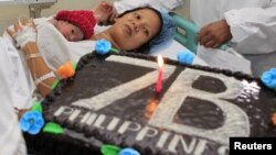 United Nations Population Fund staff gives a cake to the family of newborn baby girl named Danica Camacho, the Philippines' symbolic 'seven billionth baby' who is part of the UN's seven billion global population projection, in Fabella Maternity hospital i