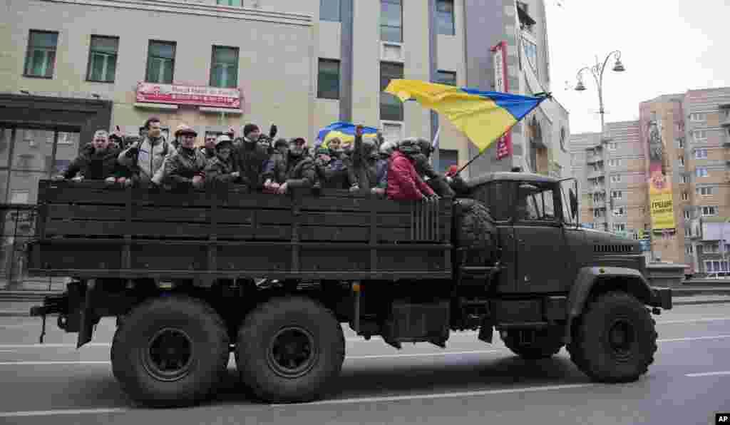 Para demonstran mengendarai truk militer di pusat kota Kyiv.