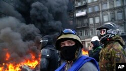 Demonstran berdiri di belakang barikade polisi anti huru-hara di Kiev, Ukraina, 25 Januari 2014. 