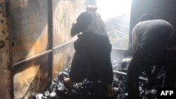 Des habitants ramassent des objets après l'incendie au marché de Madina, Conakry, le 18 mars 2018.