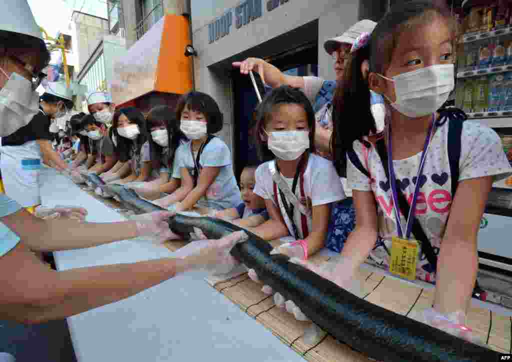 Children and volunteers help make a 120-meter long (393 ft) roll sushi to serve local people at an event in Tokyo, Japan.