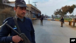 Polisi Pakistan berjaga-jaga di pos perbatasan di jalan yang mengarah ke lokasi ledakan bom di Bannu, Waziristan Utara, Pakistan (19/1). (AP/Ijaz Muhammad)
