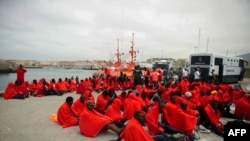 Les immigrants potentiels assis à même le sol au port de Tarifa après avoir été secourus à la côte espagnole, dans le Gibraltar, le 11 août 2014