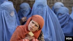 Seorang anak berdiri di depan sekelompok perempuan Afghanistan. Human Rights Watch menyebut bahwa kondisi hak perempuan di Afghanistan sangat buruk.