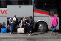 Passengers wearing masks to protect against the coronavirus disembark from a coach at the main bus station a few hours before the Spanish capital goes into a partial lockdown in Madrid, Spain, Oct. 2, 2020.