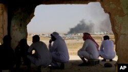 지난 3일 요르단의 자비르 국경에서 마을 주민들이 시리아에 위치한 마을에서 솟구치는 검은 연기를 바라보고 있다. 