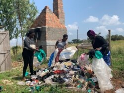 Faith Aweko, center, and her colleagues sort through garbage to pick polythene bags to be used to make plastic backpacks, in Mpigi district, Uganda. (H. Athumani/VOA)