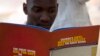 FILE - A man reads a publication by a civil society coalition on human rights and constitutional law in Kampala.