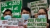 FILE - Health workers wearing protective masks hold signs during a rally outside a hospital in metropolitan Manila, Philippines, Feb. 7, 2020, demanding the government ensure their safety and raise their pay amid to the coronavirus threat.
