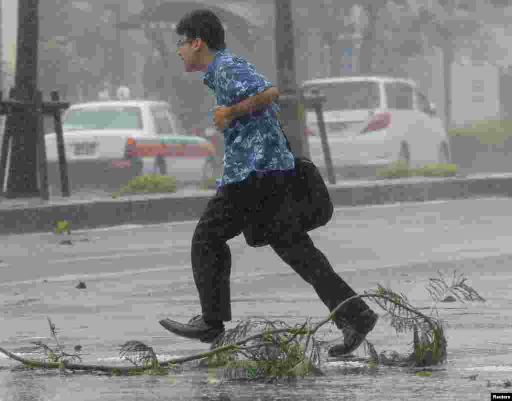 Seorang pria menyebrangi jalanan di tengah angin kencang yang disebabkan oleh Topan Neoguri di Naha, di pulau selatan Jepang, Okinawa, di foto yang diambil oleh Kyodo, 8 Juli 2014.