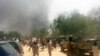 FILE - People look at smoke rising after suspected Boko Haram Islamists attack a military base in the northeast Nigerian city of Maiduguri. 