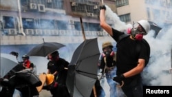 一名香港抗议者星期六(2019年8月24日)向警方扔回一枚催泪弹(路透社照片)